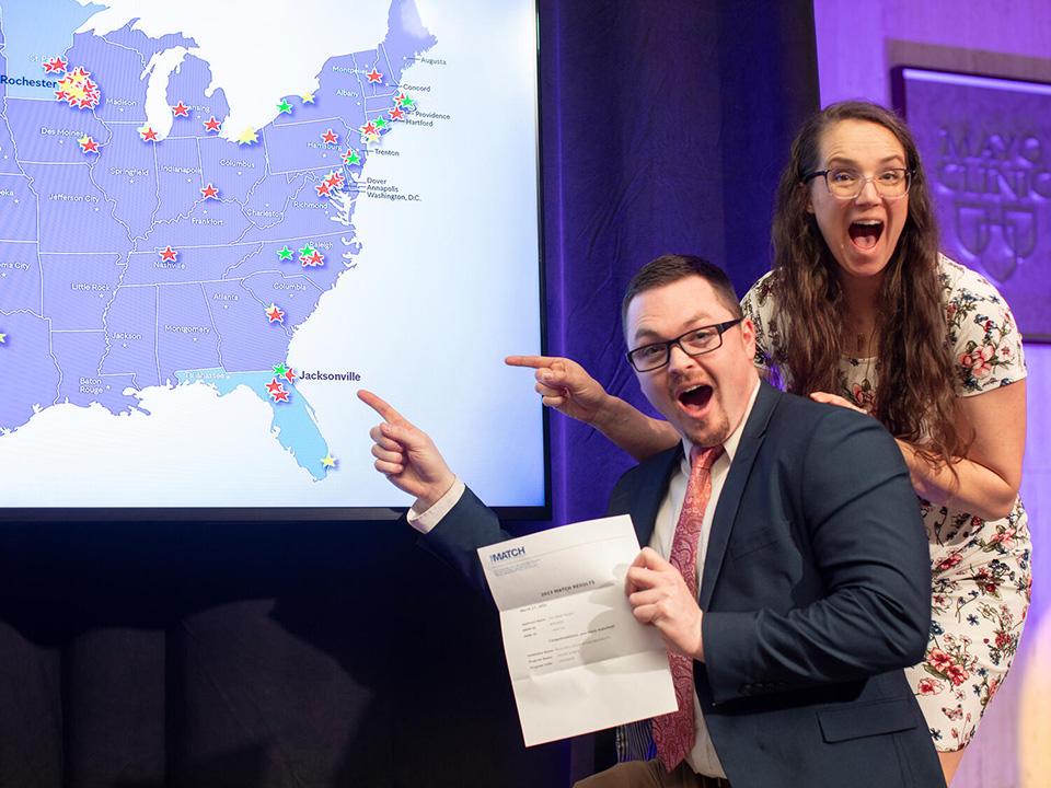 Med students point to their matches on a digital map on stage at Mayo Clinic
