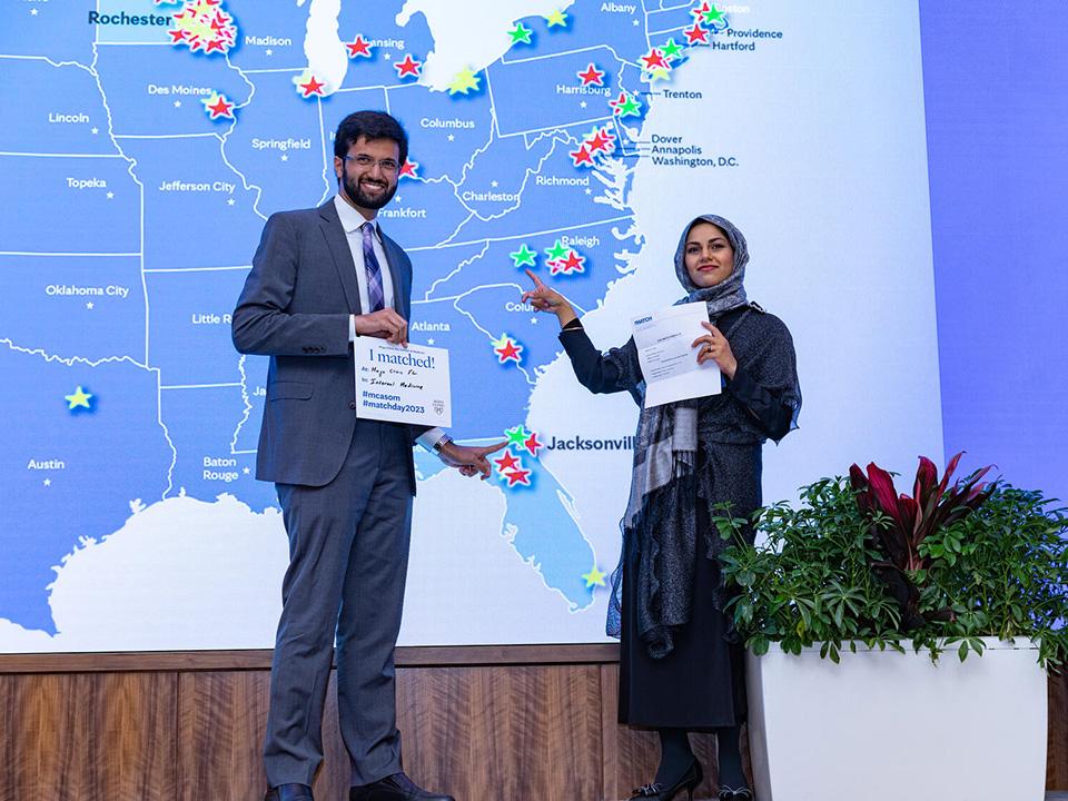 Med students point to their matches on a digital map on stage at Mayo Clinic