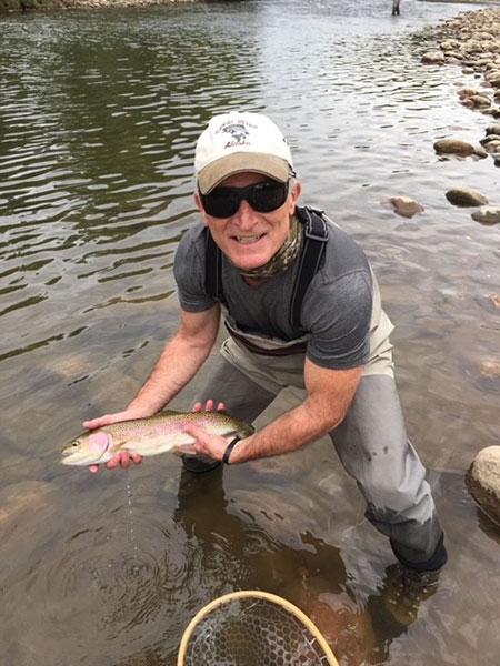 The doctor can fish! He is showing off his catch.