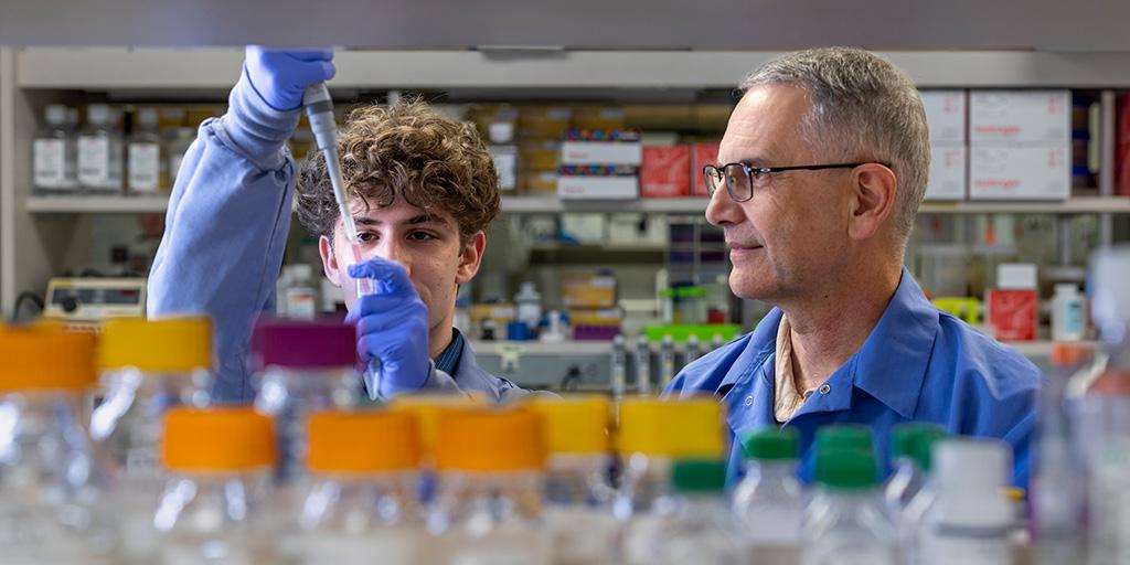 A Mayo Clinic mentor watches a SPARK intern pipette a sample in a laboratory.