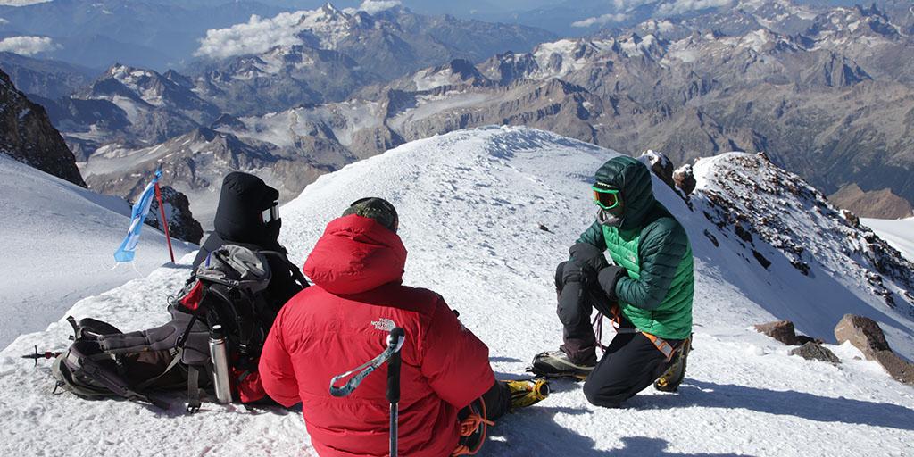 Three medical student on the summit ridge of Mount Elbrus discussing next steps.