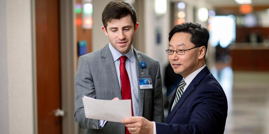 Student and faculty member in a hallway reviewing a document