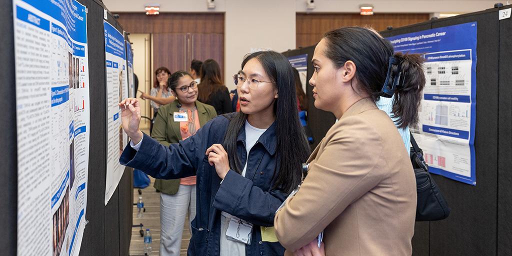 A researcher presents their poster to an attendee