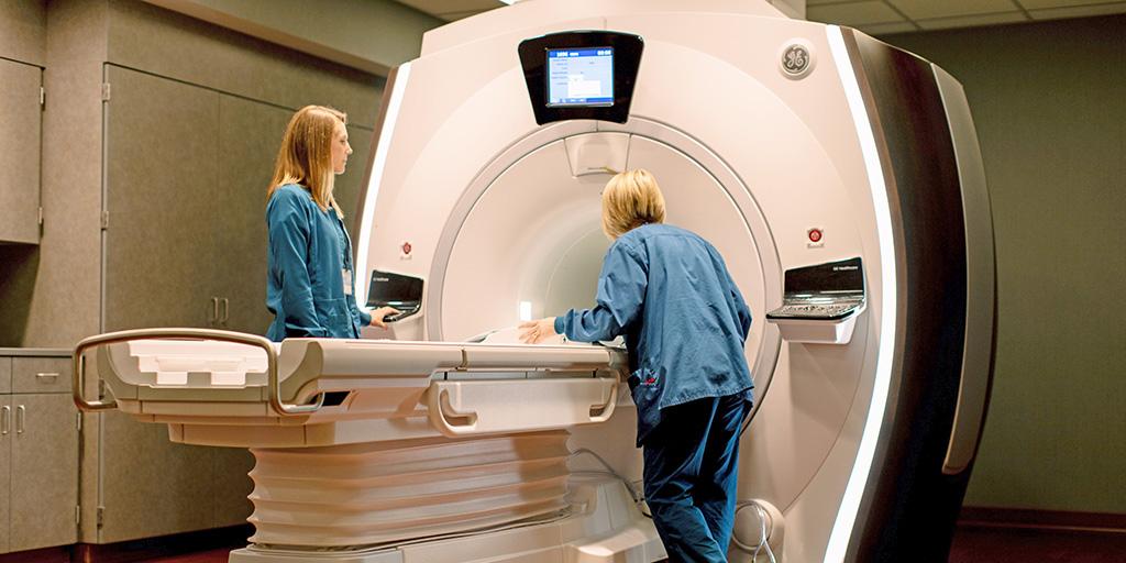 Two MRI technologists work with an MRI scanner.