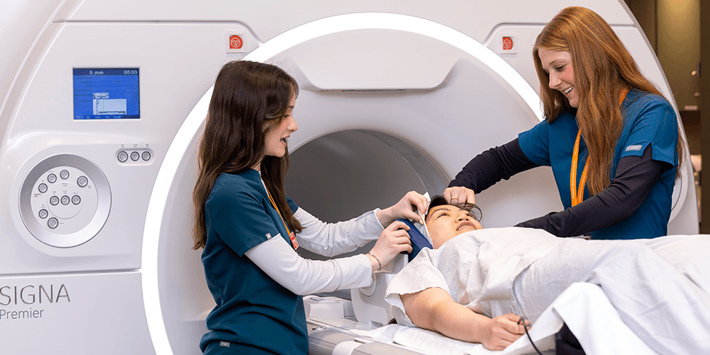 Two people helping patient into scanner
