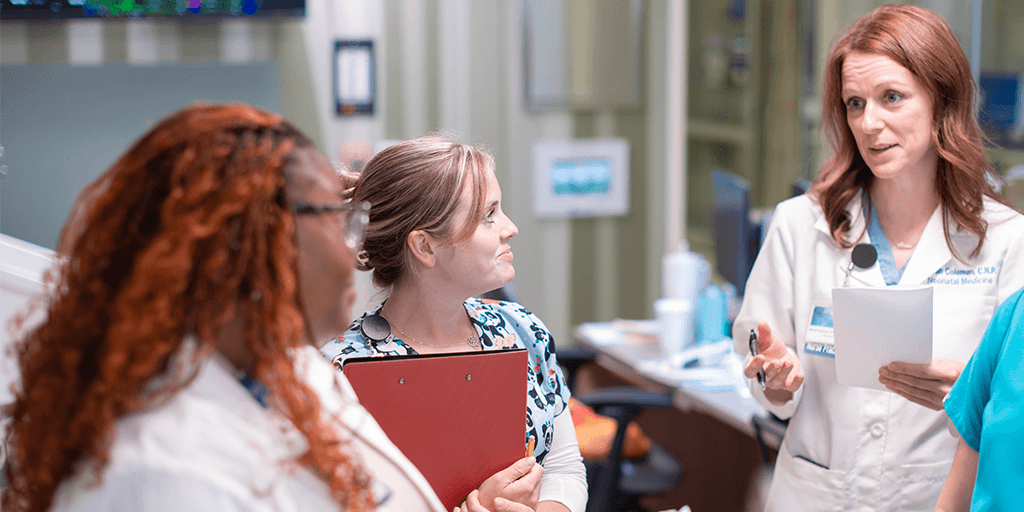 Care team members gather in an examination room and review notes on patients.