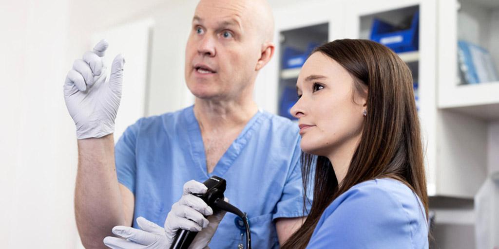 Two doctors practice a procedure inside a training lab.