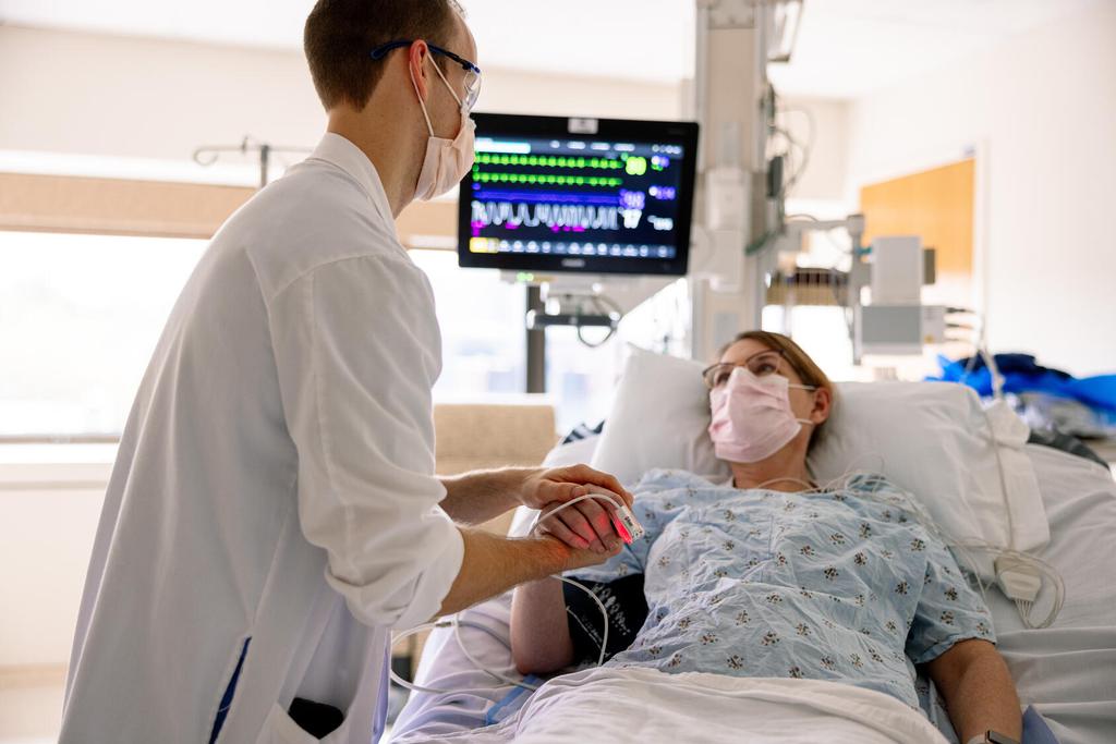 A doctor working with a patient laying in a hospital bed.