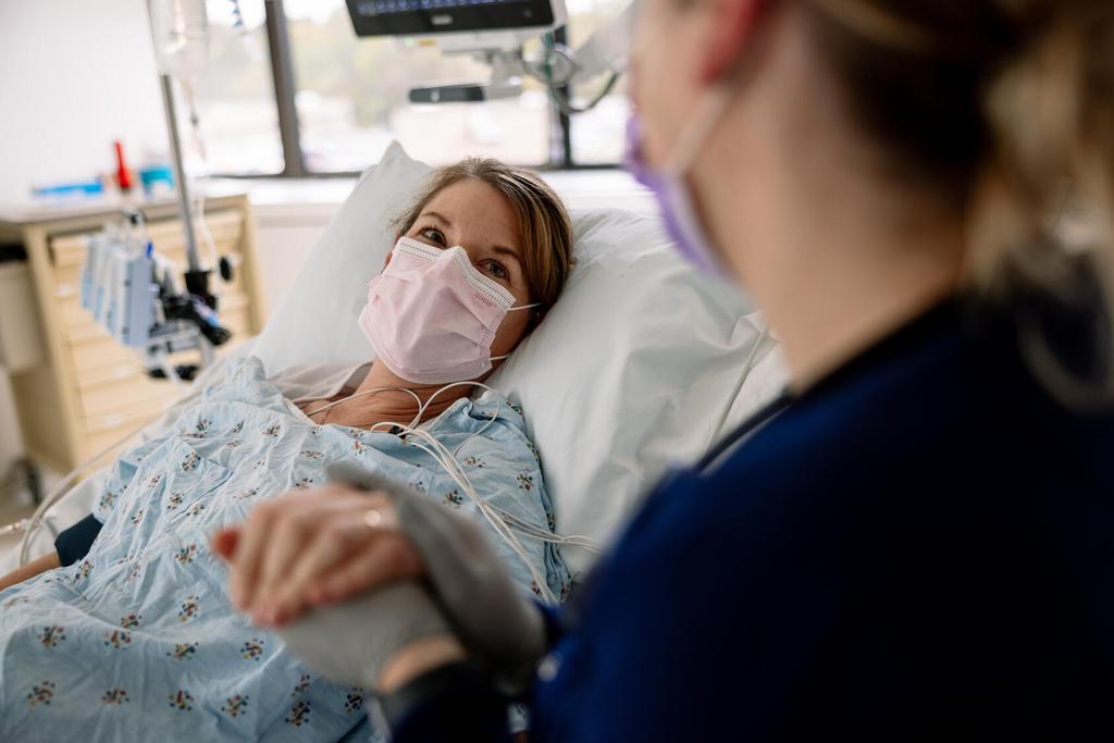 A doctor working with a patient laying in a hospital bed.