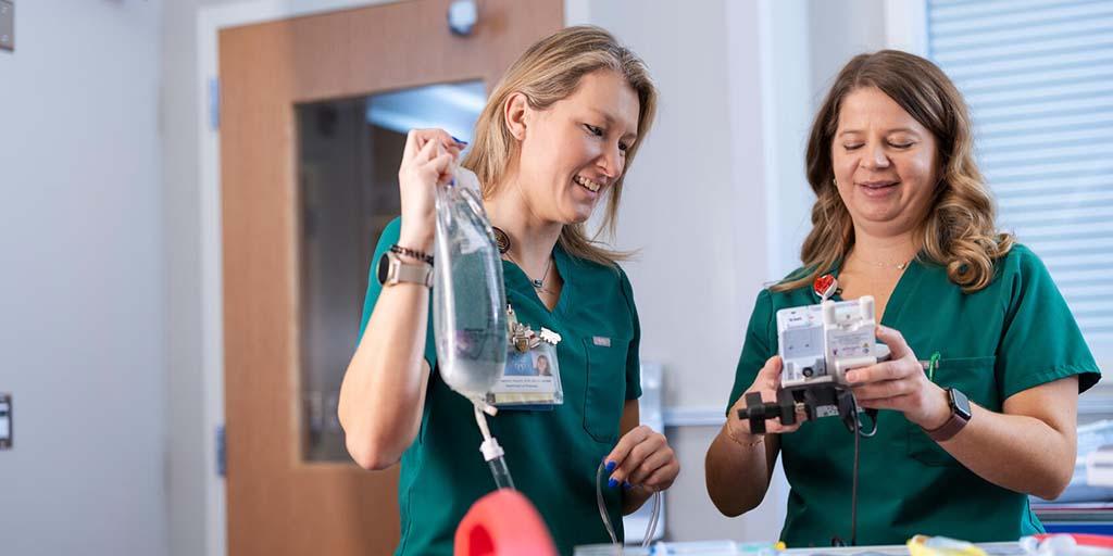 Two ER nurses prepare an IV solution.