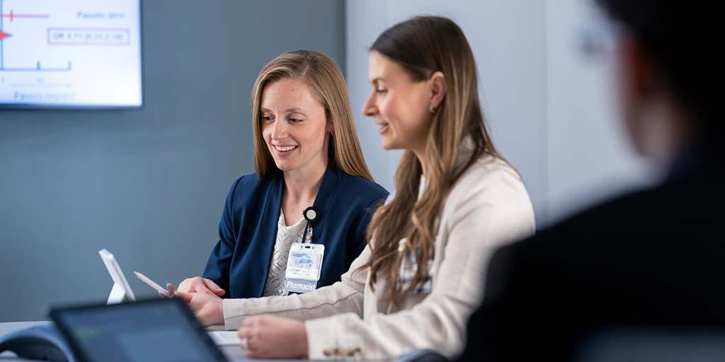 Two women look at a screen of a computer.