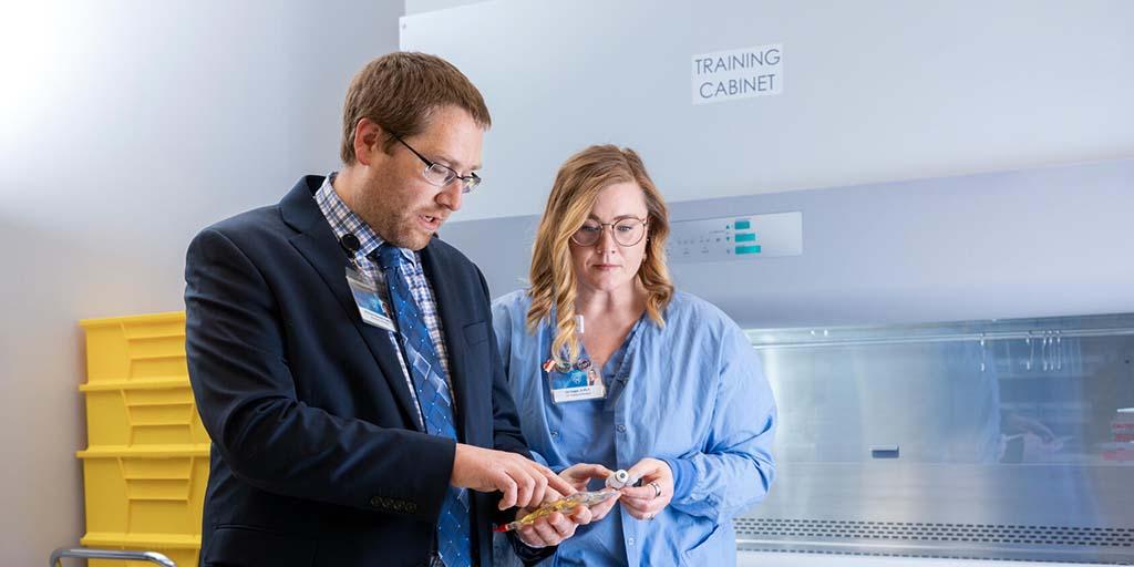 Two medical professionals look at an IV solution.