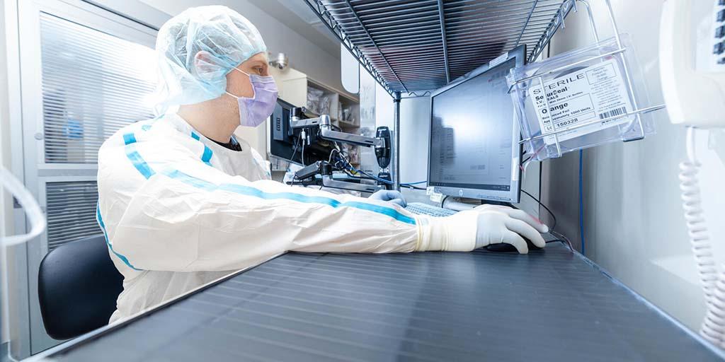 A technicians works with an automation system to prepare an IV solution.