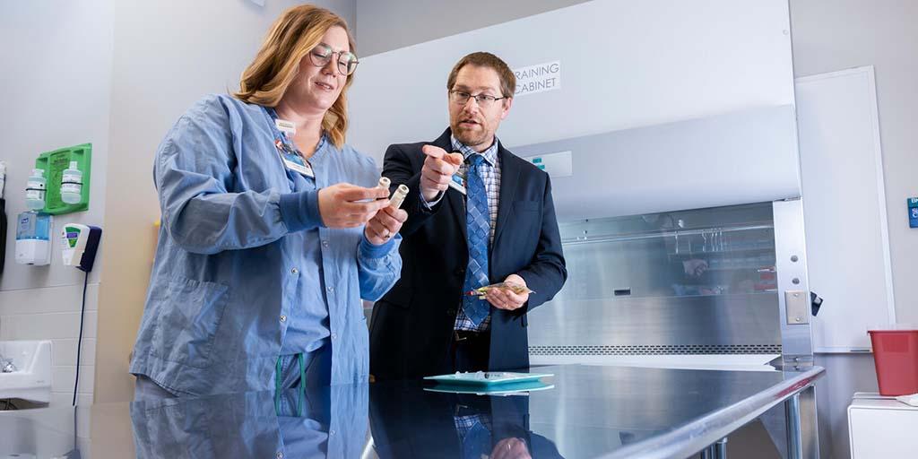 Two medical professionals look at an IV solution.