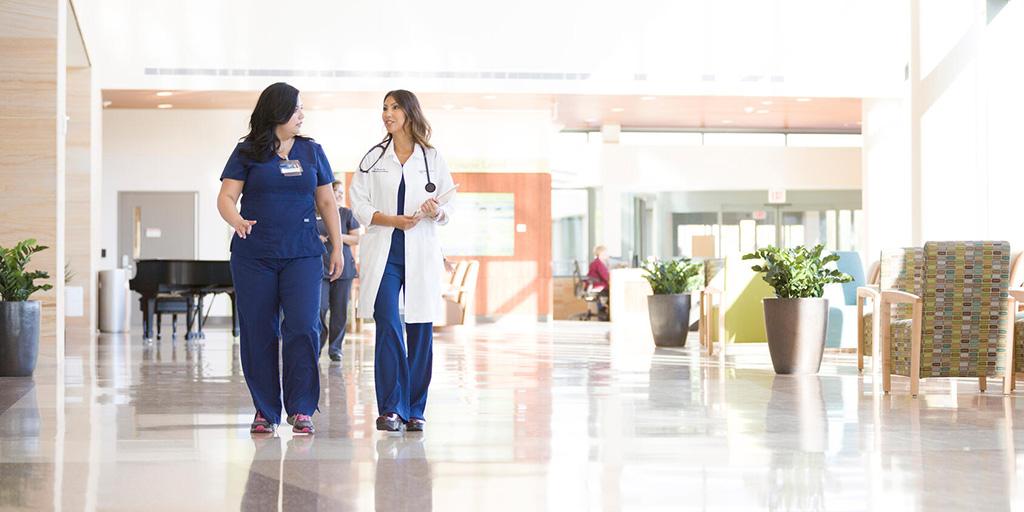Mayo Clinic physician and nurse walk down the hallway in the clinic while discussing a patient