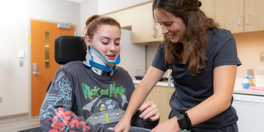 Occupational therapy fellow assists a young patient with rehab exercises at Mayo Clinic