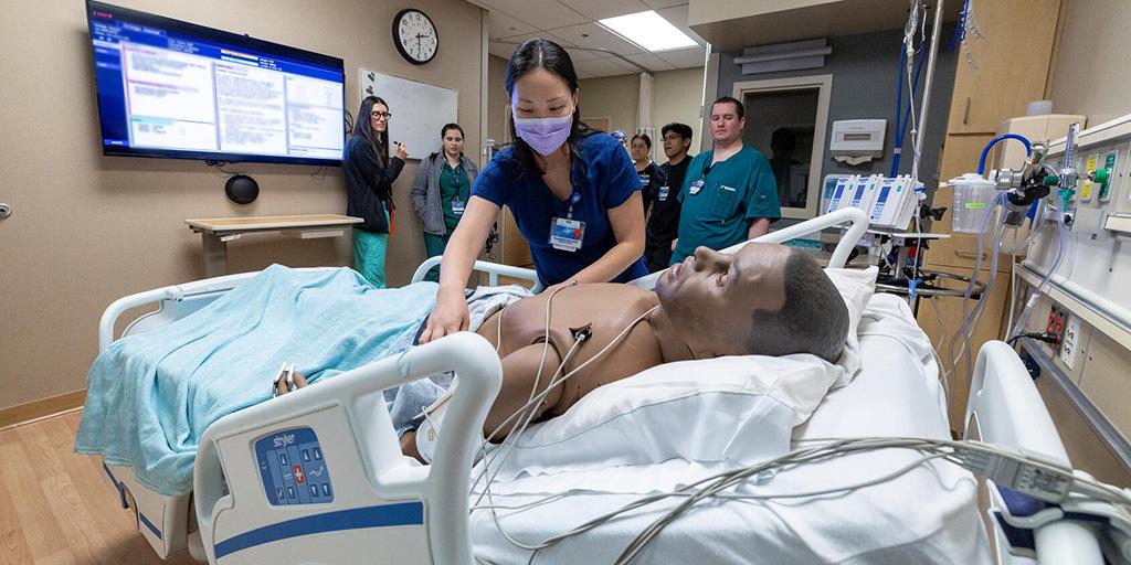 Scenario team leader approaches the manikin patient to begin the assessment in the Simulation Center.