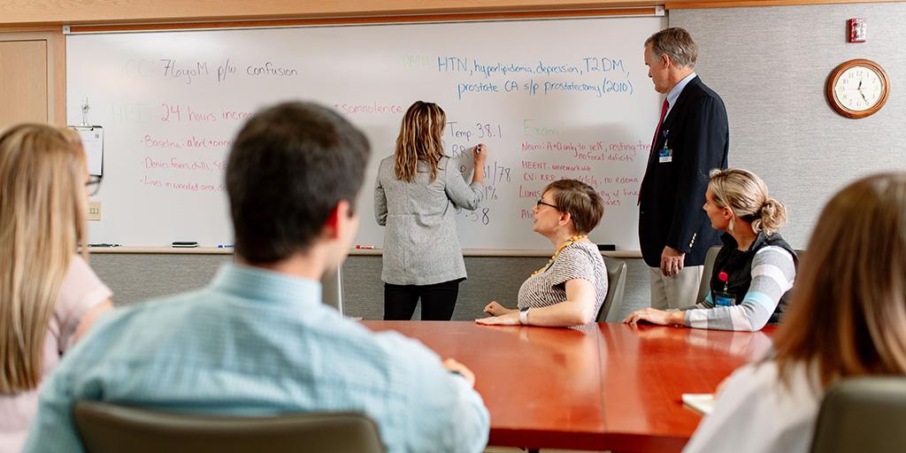 Nurse practitioners and physician assistants sit in a conference room and learn from faculty