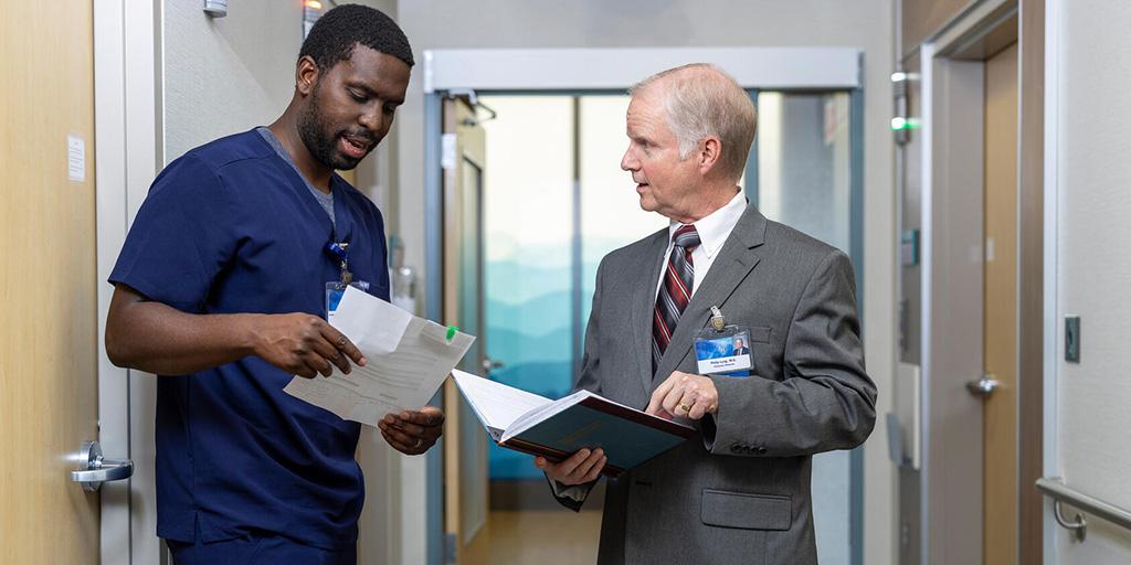An NP/PA fellow and a physician collaborate in the hallway at Mayo Clinic