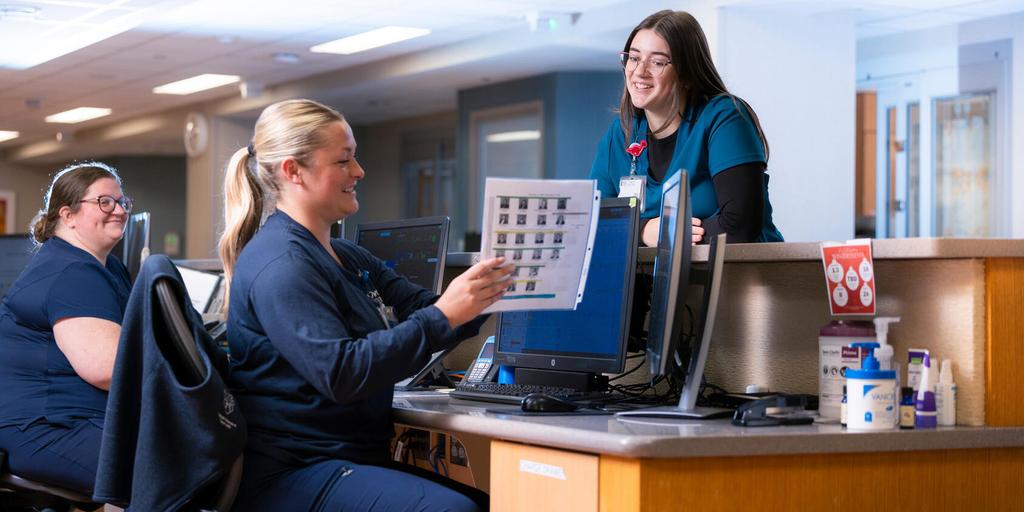Medical assistants and nurses speak at the patient care desk at Mayo Clinic Hospital