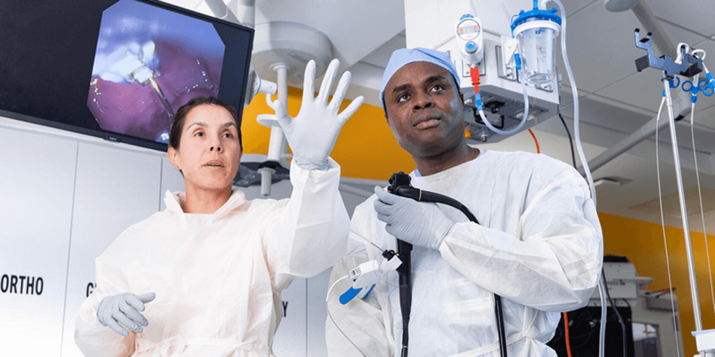 Two fellows in lab coats and gloves working with equipment