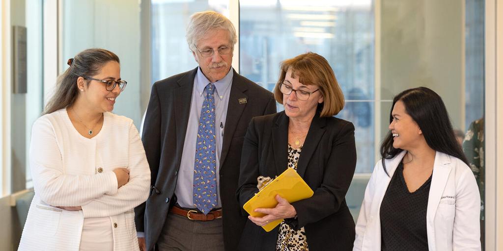 Four people from the Advanced Inflammatory Bowel Disease Fellowship program at Mayo Clinic in Jacksonville, Florida, held a discussion as they walked down a hallway.
