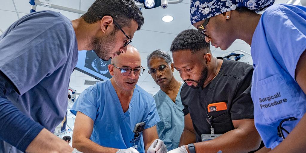Five people from the Anesthesiology Residency program in Jacksonville, Florida, working in the lab and performing a procedure.