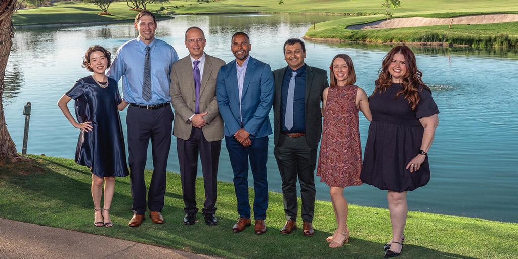 A group of alumni poses outside for a group photo.