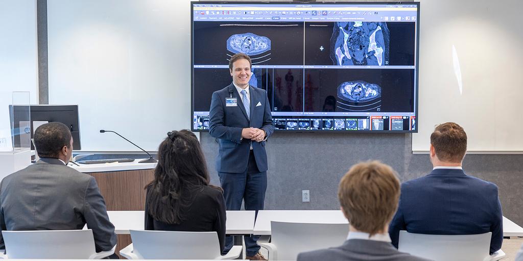 Josh Sellwood, DO, Diagnostic Radiology resident, reviews diagnostic imaging with his colleagues in a lecture hall.