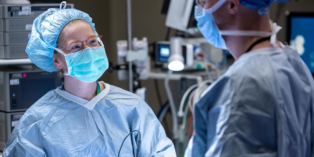 Two doctors practice a procedure in an operating room.