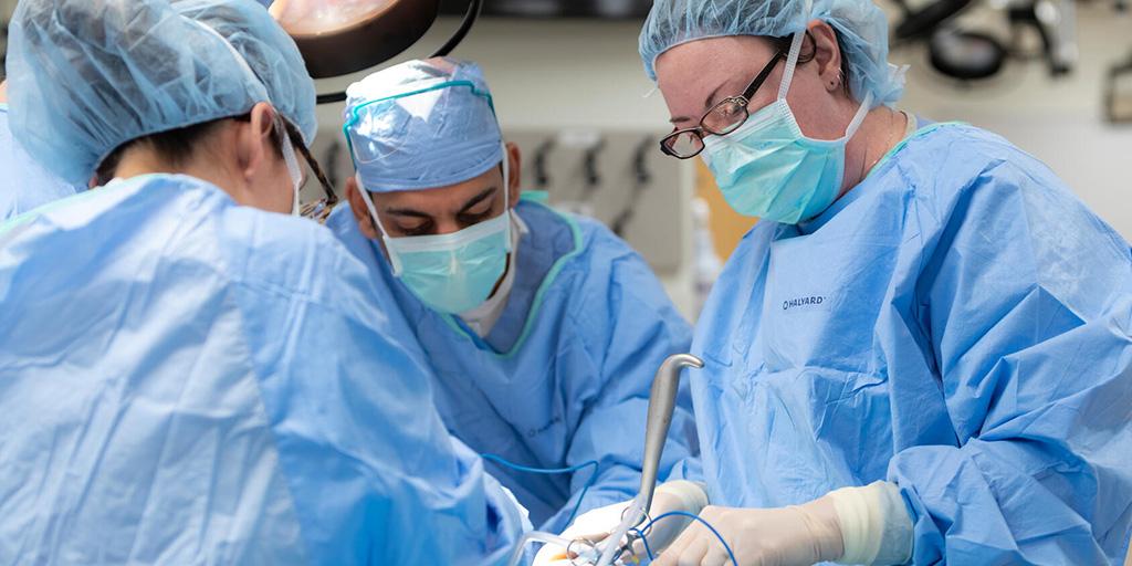 Four doctors perform a procedure in an operating room.