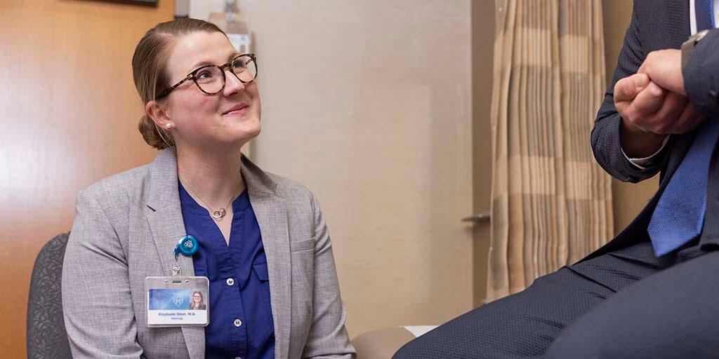 A neurology consultant uses a reflex hammer to test the knee reflex of a patient.