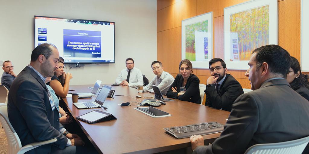 Eleven people from the Hematology/Oncology Fellowship program in Jacksonville, Florida, are in a conference room sitting at a table and having a discussion.