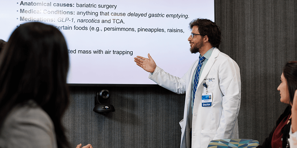 Fellow speaking to colleagues in a conference room