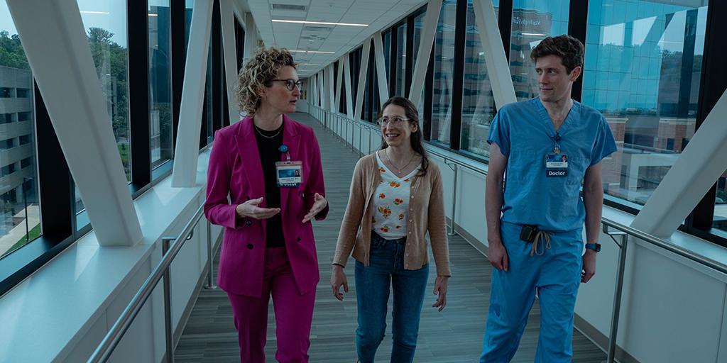 Doctors chat as they walk across a skyway tunnel.