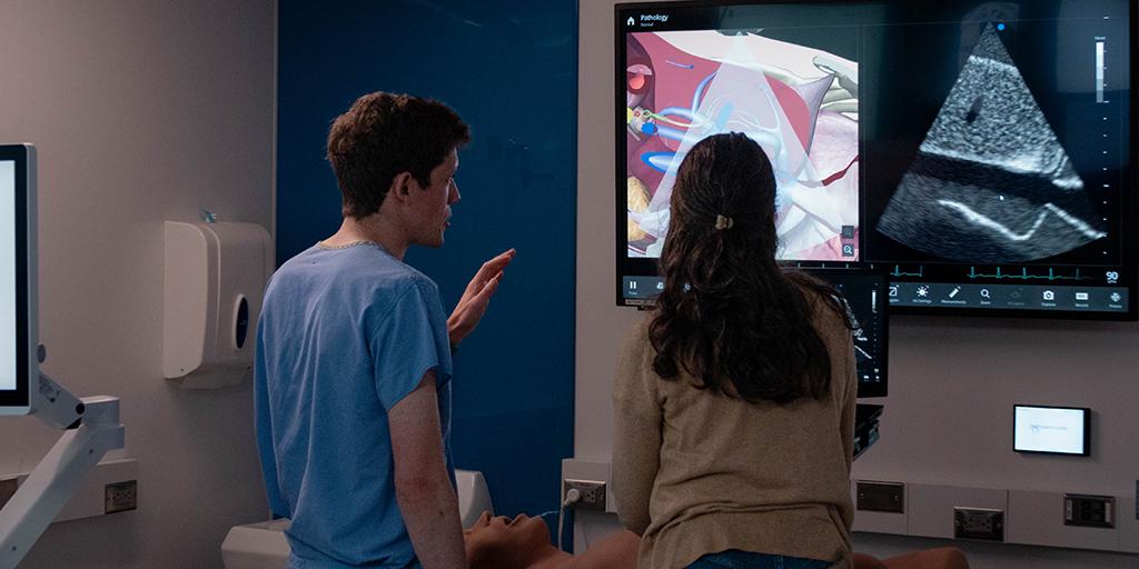 Two internal medicine residents look at an image on a screen.