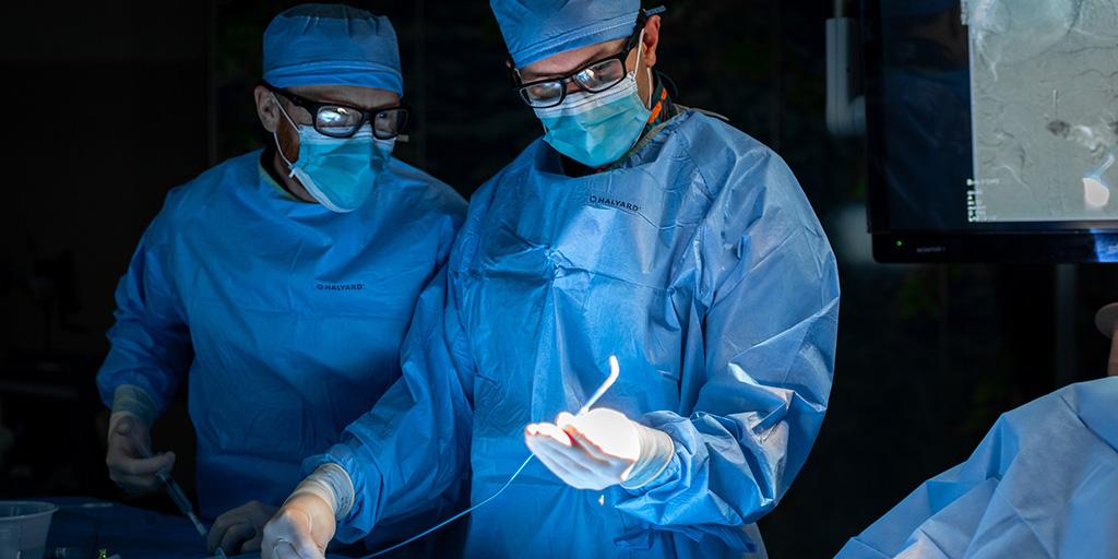 Two people in an operating room performing a procedure.