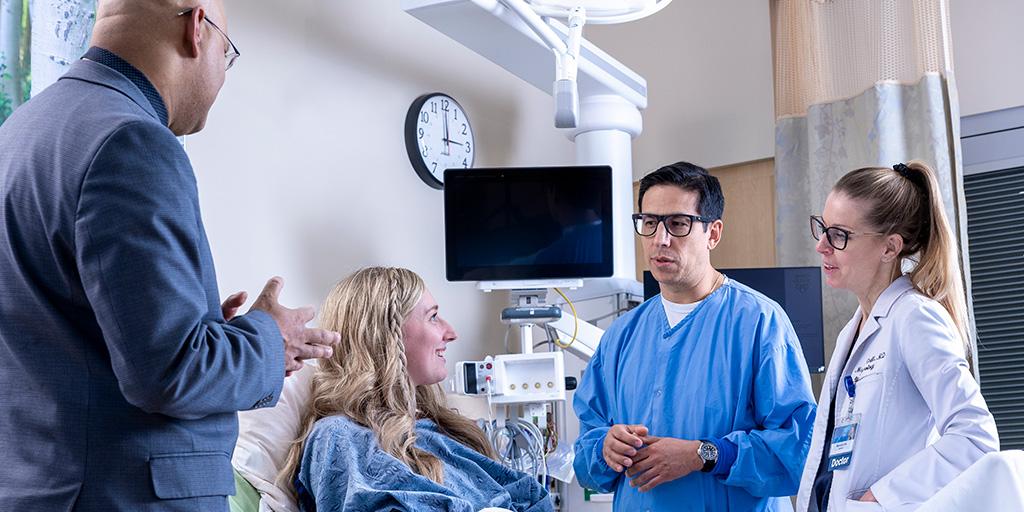 Three fellows from the Neurohospitalist Fellowship program talking with a patient in her room