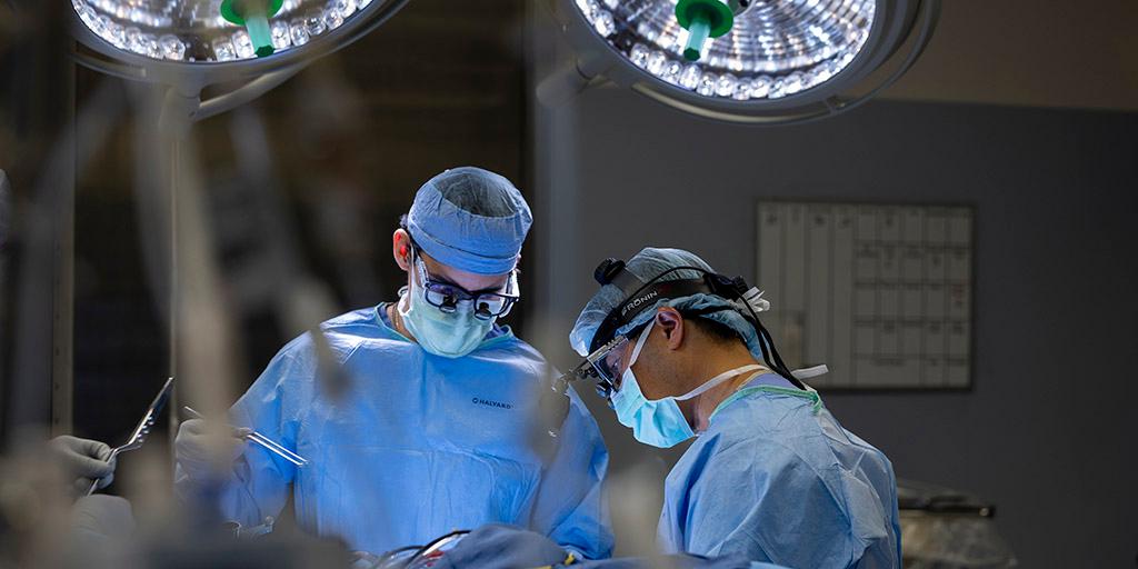 Two surgeons work under the lights of the operating room.