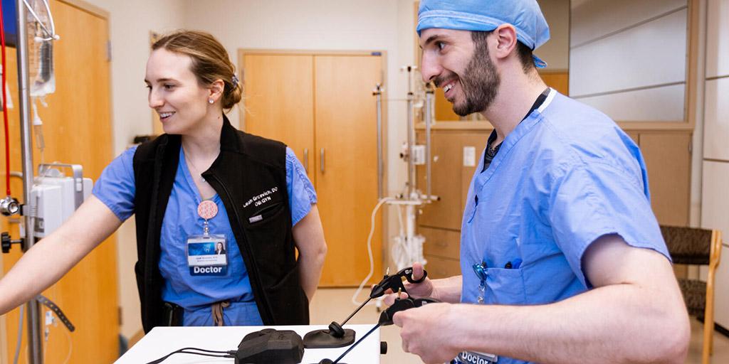Two doctors practice a laparoscopy procedure.