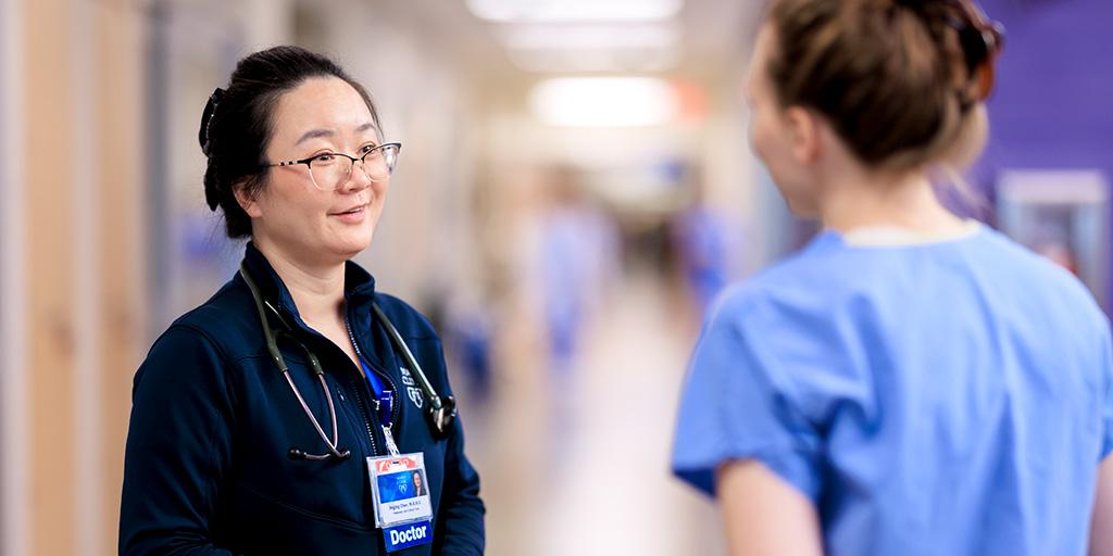 A felllow and doctor from Pulmonary and Critical Care Medicine Fellowship converse in hallway.