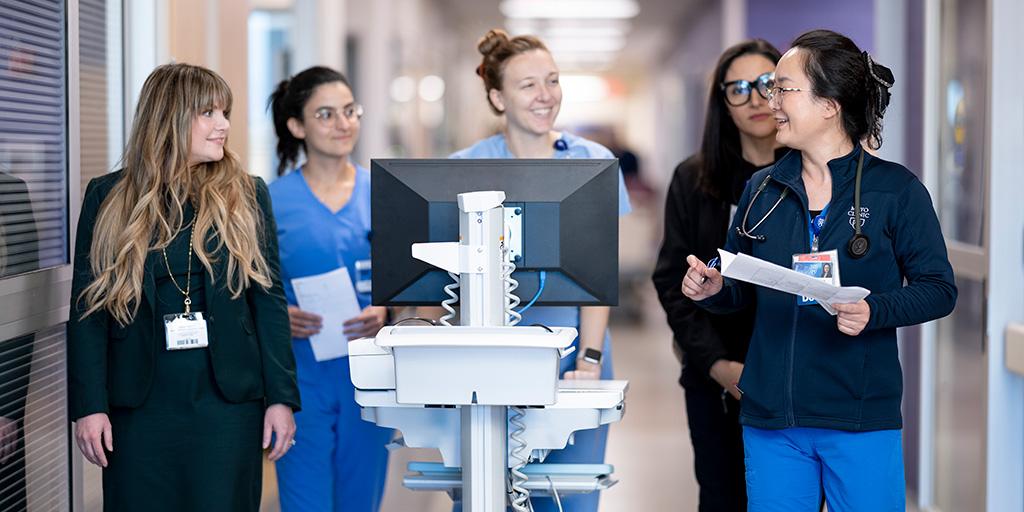 Five fellows from Pulmonary and Critical Care Fellowship Arizona walking down hallway with mobile computer station.
