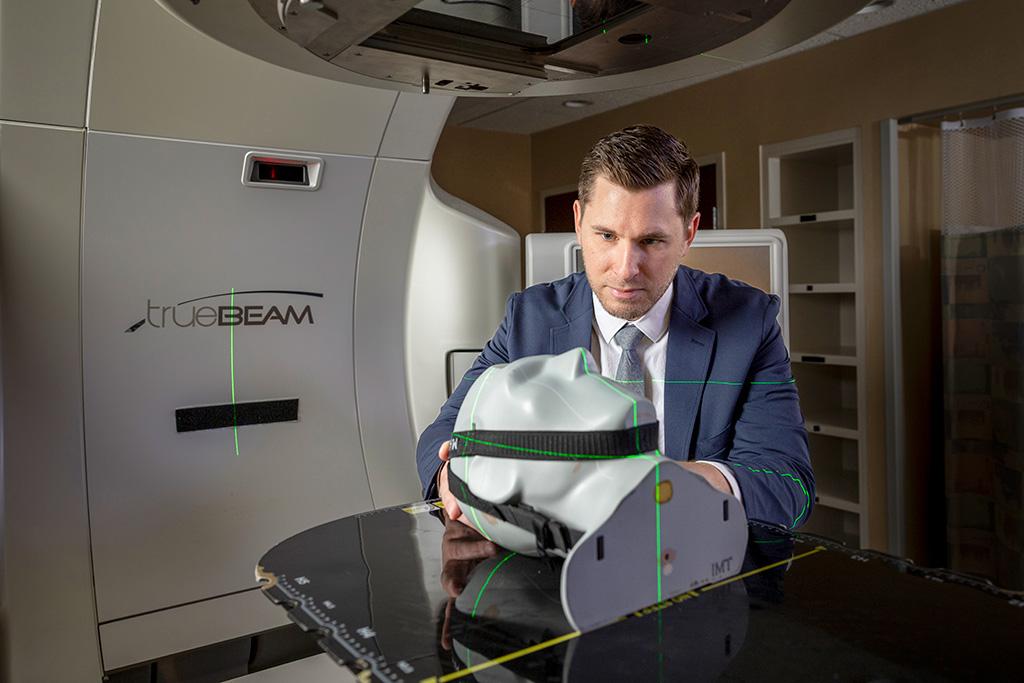 A person in a radiology room demonstrating use of a radiology imaging machine.