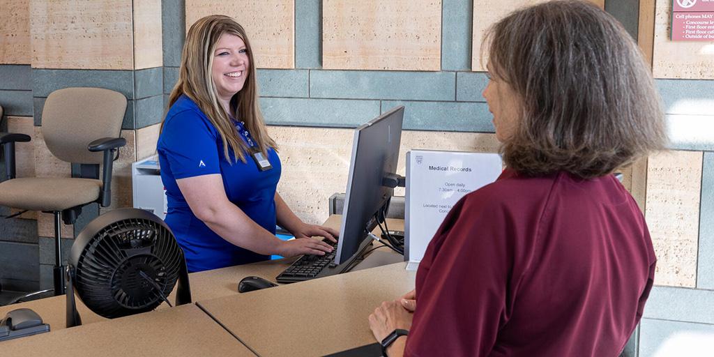 An employee at a front desk assists a Mayo Clinic visitor.