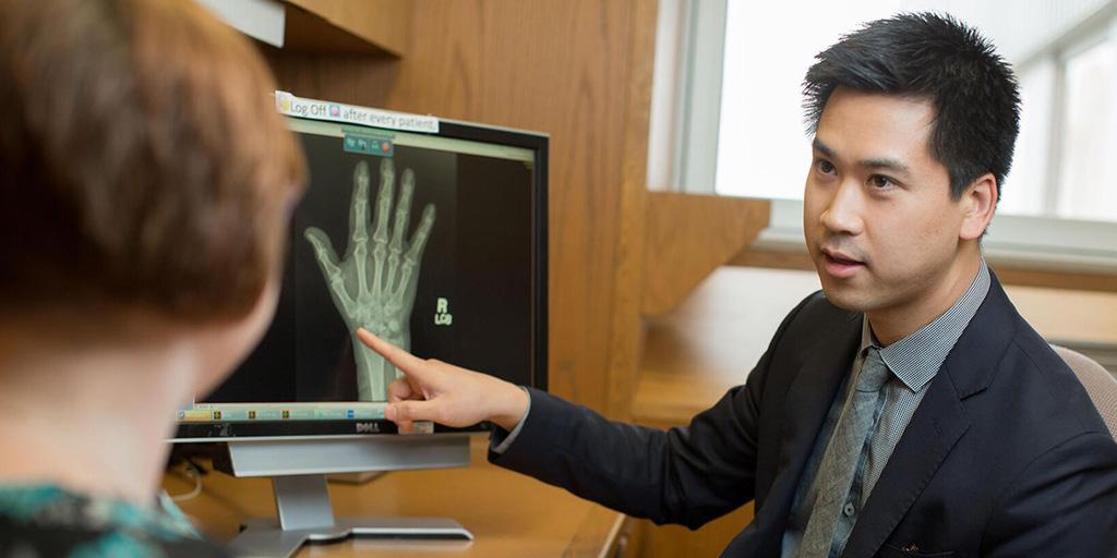 A doctors shows an xray of a hand to a patient.