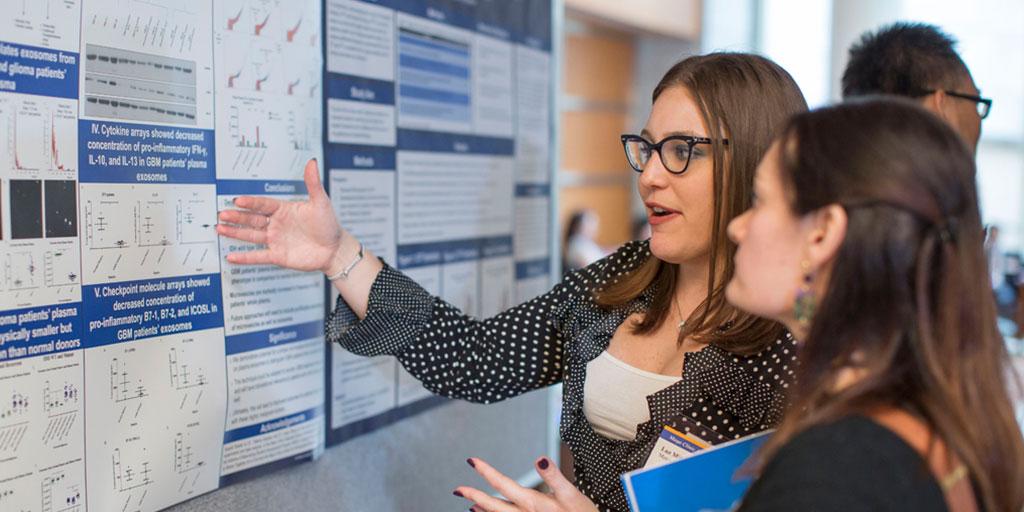 Poster hall with students review research poster