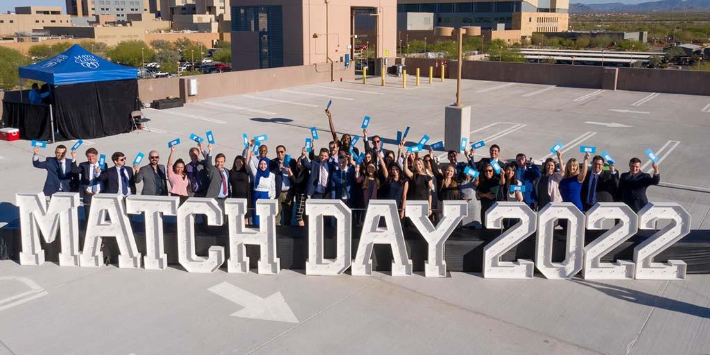 Match Day students with their envelopes in front of a sign