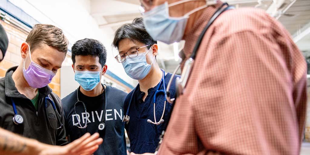 Casey Caldwell, M.D., and medical students examine a young man’s hand while working in a community outreach program.