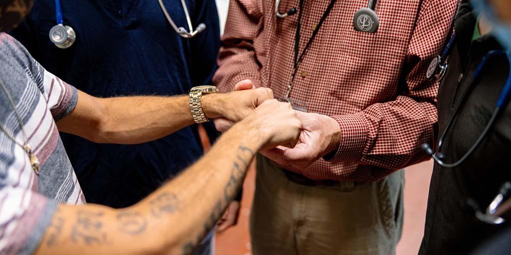 A doctor and medical students examine a young man’s hand while working in a community outreach program