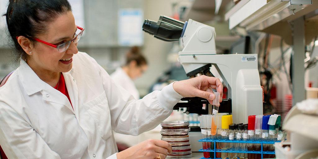 Dr. Robin Patal looking at slides with a microscope in the lab at Mayo Clinic